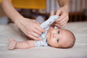 Mutter zieht Baby Kleidung an
