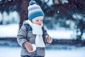 Kleinkind spielt warm angezogen im Schnee