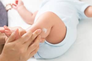 Baby wird von Mutter eingecremt