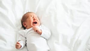 Baby liegt auf dem Bett und schreit
