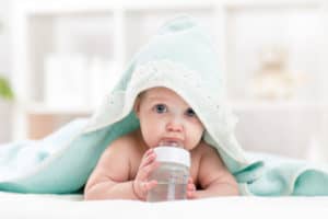 Baby ist in einem Handtuch eingewickelt und trinkt aus Fläschchen