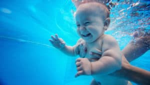 Baby taucht und lacht unter Wasser