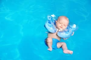 Baby hat ein Schwimmring um den Kopf und treibt auf dem Wasser