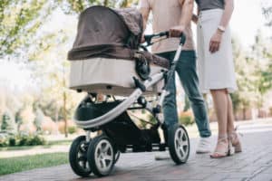 Eltern sind mit ihrem Baby im Kinderwagen draußen spazieren