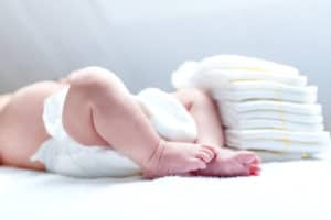 Baby liegt auf dem Wickeltisch und hat eine Windel an