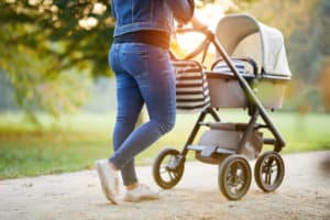 Mutter ist draußen mit Kinderwagen unterwegs