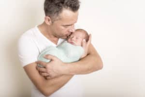 Vater hält Baby gepuckt auf dem Arm