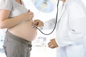 Arzt untersucht Bauch einer schwangeren Frau