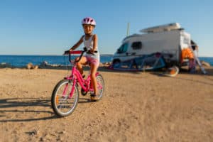 Kind fährt im Urlaub vor einem Wohnmobil Fahrrad in Kroatien