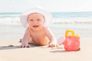 Baby liegt am Strand und spielt