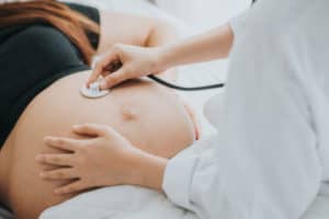 Schwangere Frau wird von Ärztin bei einer Vorsorgeuntersuchung untersucht
