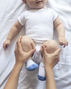 Mutter hilft dem Baby bei seinen Verstopfungen, indem sie dem Baby seine Beine anwinkelt