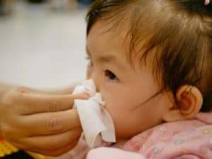 Baby mit Erkältung bekommt die Nase geputzt
