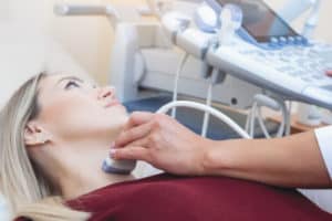 Bei einer Frau wird ein Ultraschall an der Schilddrüse durchgeführt