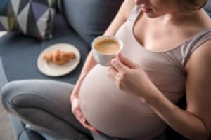 Schwangere Frau trinkt einen Kaffee